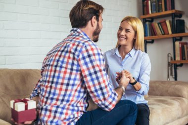 gülümseyen genç adam şaşırtıcı neşeli kadın evde hediye kutusu