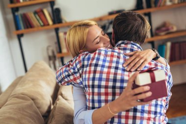 gülümseyen genç adam şaşırtıcı neşeli kadın evde hediye kutusu