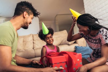 Mutlu siyah aile evde. Afro-Amerikan baba, anne ve Çocuk Doğum günü, kutlama partide eğleniyor. Genç kadın kızına hediye vermek