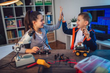 Mutlu gülümseyen erkek ve kız teknik robot oyuncak ve yapmak oluşturur. Tablo ayrıntılarını tam teknik oyuncak