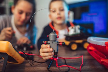 Mutlu gülümseyen erkek ve kız teknik robot oyuncak ve yapmak oluşturur. Tablo ayrıntılarını tam teknik oyuncak