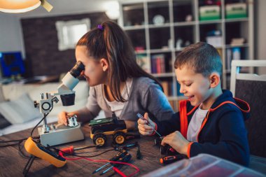 Mutlu gülümseyen erkek ve kız teknik robot oyuncak ve yapmak oluşturur. Tablo ayrıntılarını tam teknik oyuncak