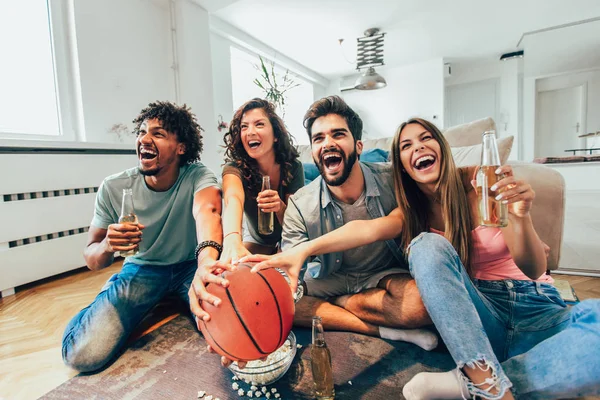 Happy friends or basketball fans watching basketball game on tv and celebrating victory at home.Friendship, sports and entertainment concept.