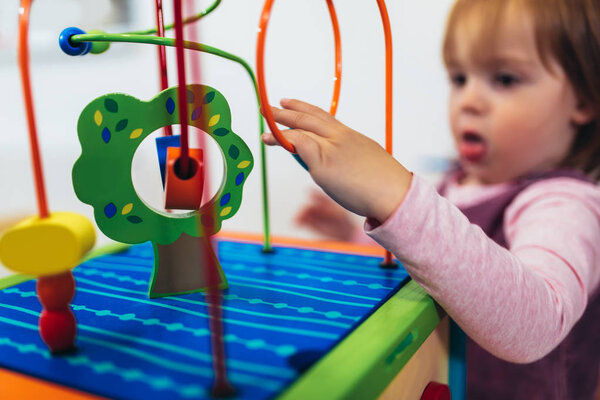Cute child playing on table indoor, selective focus.