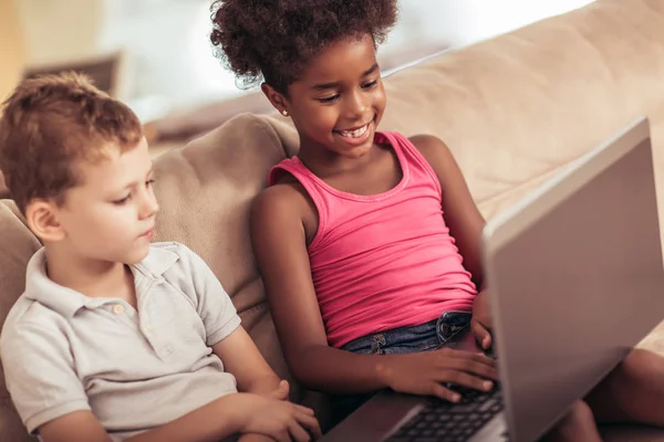 Beyaz çocuk ve Afro-Amerikan Kız evde laptop kullanma.