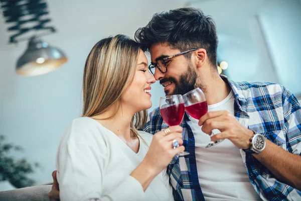 家でワインを楽しむ若いカップル 彼らは互いの近くに座っている 赤ワインを飲む — ストック写真