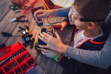 Mutlu gülümseyen erkek ve kız teknik robot oyuncak ve yapmak oluşturur. Tablo ayrıntılarını tam teknik oyuncak
