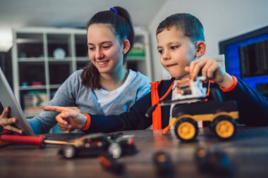 Mutlu gülümseyen erkek ve kız teknik robot oyuncak ve yapmak oluşturur. Tablo ayrıntılarını tam teknik oyuncak