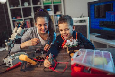 Mutlu gülümseyen erkek ve kız teknik robot oyuncak ve yapmak oluşturur. Tablo ayrıntılarını tam teknik oyuncak