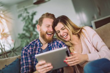 Çift kanepede oturan ve tablet eğleniyor, kullanma aşık. 