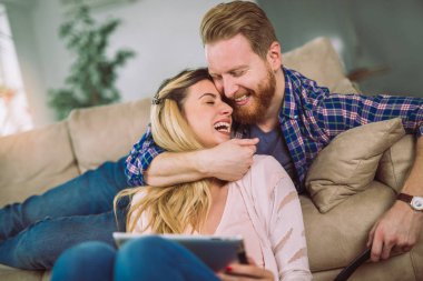 Çift kanepede oturan ve tablet eğleniyor, kullanma aşık. 