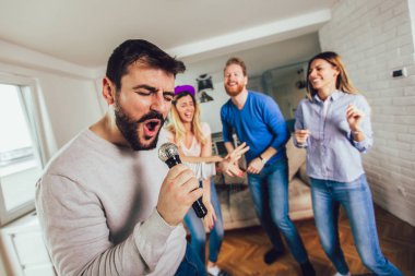Evde karaoke yapan bir grup arkadaş. Arkadaşlık kavramı, ev eğlencesi ve insanlar
