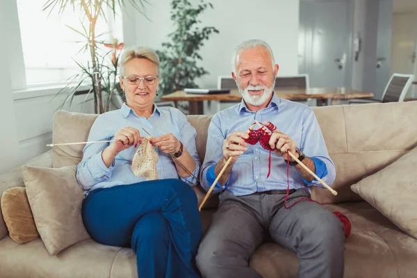 Senior woman teaching her husband the art of knitting woollen clothes.