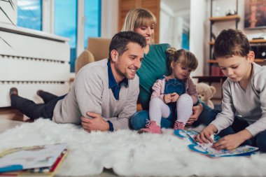 Evde oturma odasında katında eğleniyor, gülerek mutlu bir aile.