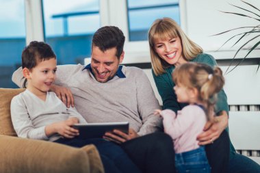 Eğlenceli, seçici odak sahip evde, tablet ile oynarken mutlu bir aile portresi