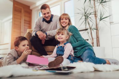 Evde oturma odasında katında eğleniyor, gülerek mutlu bir aile.