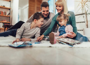 Evde oturma odasında katında eğleniyor, gülerek mutlu bir aile.