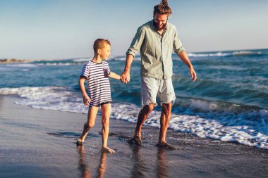 Çalışan ve kum ve güneşli bir plaj dalgalar eğlenerek mutlu baba ve oğlu, erkek ve çocuk çocuk,