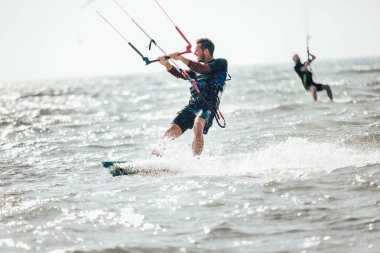 Profesyonel kiter zor hüner güzel bir arka plan üzerinde yapar. Kitesurfing Kiteboarding eylem fotoğraflar adam dalgalar arasında hızlı bir şekilde gider