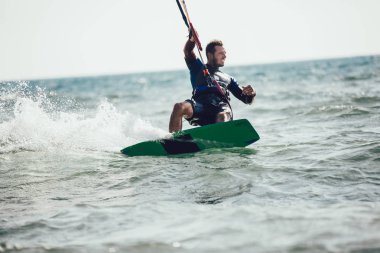 Profesyonel kiter zor hüner güzel bir arka plan üzerinde yapar. Kitesurfing Kiteboarding eylem fotoğraflar adam dalgalar arasında hızlı bir şekilde gider
