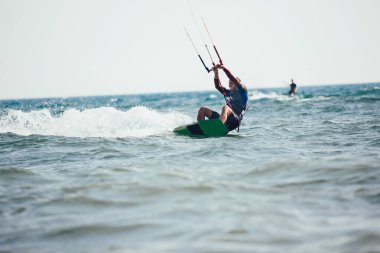 Profesyonel kiter zor hüner güzel bir arka plan üzerinde yapar. Kitesurfing Kiteboarding eylem fotoğraflar adam dalgalar arasında hızlı bir şekilde gider