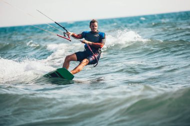 Profesyonel kiter zor hüner güzel bir arka plan üzerinde yapar. Kitesurfing Kiteboarding eylem fotoğraflar adam dalgalar arasında hızlı bir şekilde gider