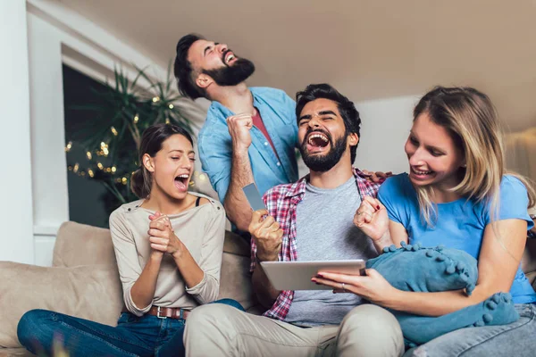 Four Casual Happy Friends Laughing Shopping Online Together Tablet Sitting — Stock Photo, Image