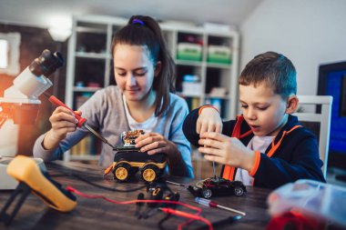 Mutlu gülümseyen erkek ve kız teknik robot oyuncak ve yapmak oluşturur. Tablo ayrıntılarını tam teknik oyuncak