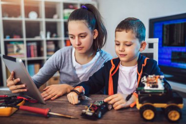 Mutlu gülümseyen erkek ve kız teknik robot oyuncak ve yapmak oluşturur. Tablo ayrıntılarını tam teknik oyuncak