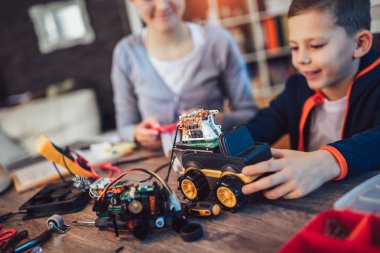 Mutlu gülümseyen erkek ve kız teknik robot oyuncak ve yapmak oluşturur. Tablo ayrıntılarını tam teknik oyuncak