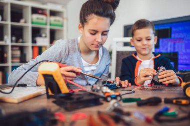 Mutlu gülümseyen erkek ve kız teknik robot oyuncak ve yapmak oluşturur. Tablo ayrıntılarını tam teknik oyuncak