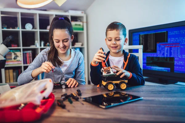 Mutlu gülümseyen erkek ve kız teknik robot oyuncak ve yapmak oluşturur. Tablo ayrıntılarını tam teknik oyuncak