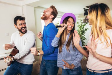 Evde karaoke yapan bir grup arkadaş. Arkadaşlık kavramı, ev eğlencesi ve insanlar