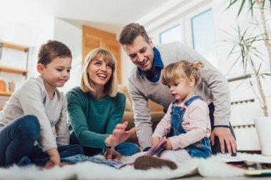Mutlu aile eğleniyor evde, oturma odasında katında gülüyor, seçici odak.