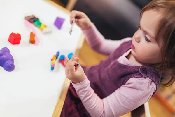 Niña Está Jugando Con Plastilina Mientras Está Sentado Mesa Habitación —  Fotos de Stock