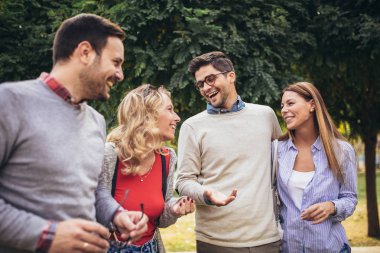 Bir grup genç parkta yürüyor. Arkadaşlar dışarıda eğleniyor.