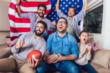 TV izlerken ve tezahürat erkek arkadaşlar evde kanepe üzerinde oyunlar spor. Amerikan futbolu maçı izlerken arkadaş grubu.