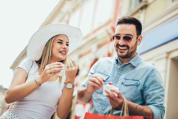 Χαμογελώντας ζευγάρι σε αγορές με παγωτό και τσάντες για ψώνια — Φωτογραφία Αρχείου
