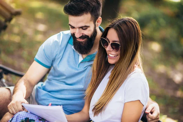 Mooie jonge paar zittend op een bankje in het park, zijn ze — Stockfoto