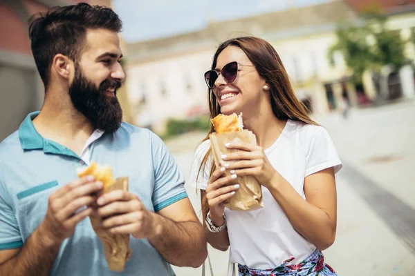 Young couple is eating sandwiches and having a great time — Stock Photo, Image