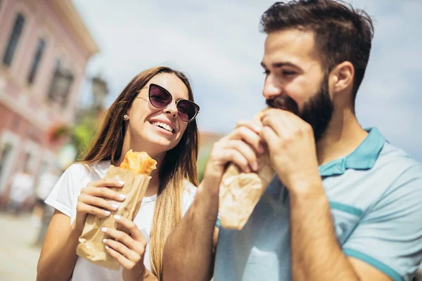 Casal jovem está comendo sanduíches e se divertindo muito — Fotografia de Stock