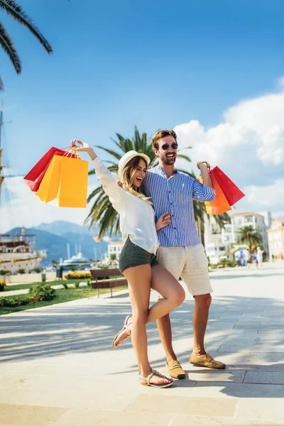 Feliz pareja joven con bolsas de compras caminando por el puerto de un — Foto de Stock