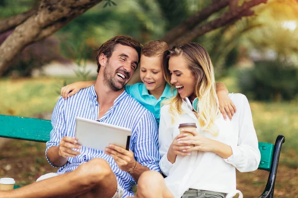 Joven familia hablando y mirando tableta digital en el parque — Foto de Stock