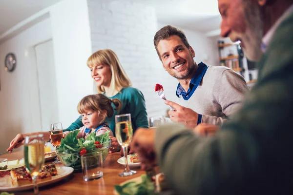 Flergenerasjonsfamilie nyter måltidet rundt bordet hjemme – stockfoto