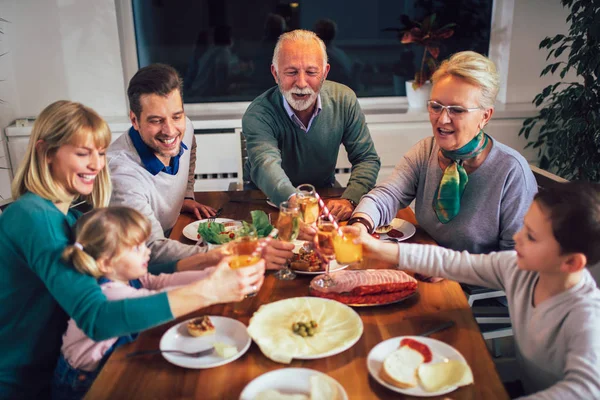 Multi generatie familie genieten van maaltijd rond tafel thuis — Stockfoto