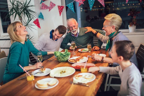 Multi generatie familie genieten van maaltijd rond tafel thuis — Stockfoto