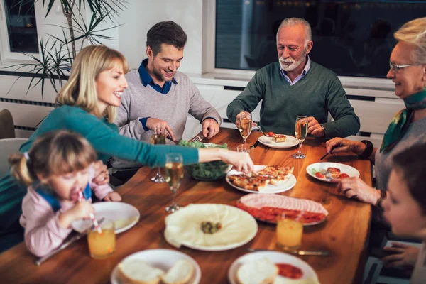 Flergenerasjonsfamilie nyter måltidet rundt bordet hjemme – stockfoto