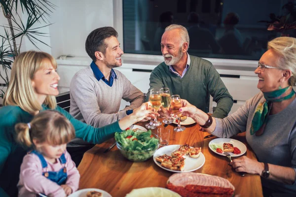 Сім'я насолоджуючись їжею навколо столу вдома — стокове фото