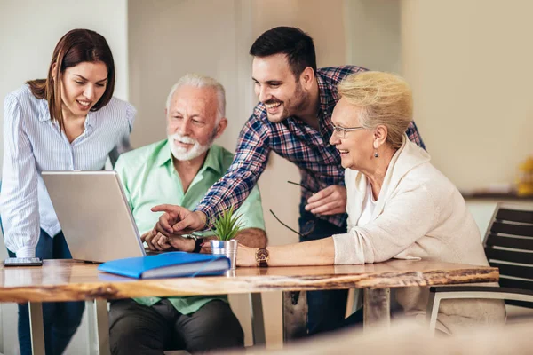 Молодые добровольцы помогают пожилым людям за компьютером. Молодые люди — стоковое фото