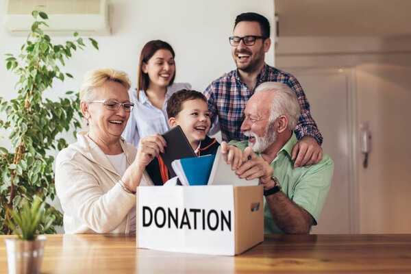 Family donating unwanted items. They are holding box with stuffs